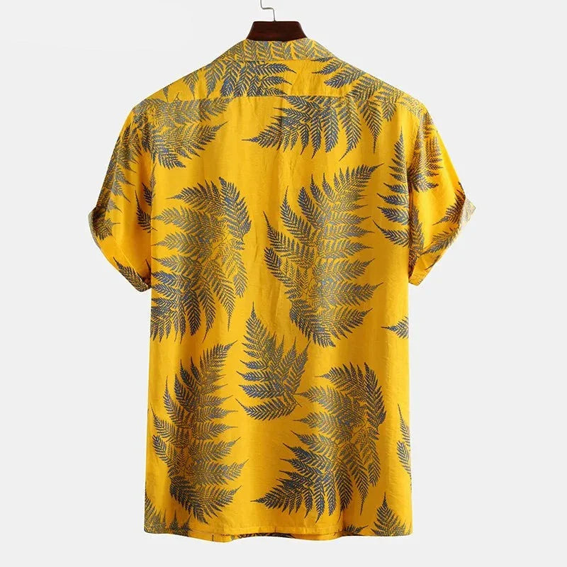 A classic design cotton shirt with short sleeves in yellow, featuring large dark green and blue fern leaves, is shown from the back on a hanger against a plain white background—perfect for a casual brunch.