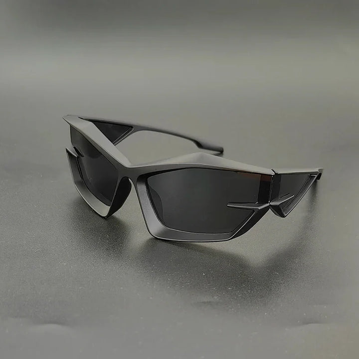 Angular, futuristic black sunglasses with geometric frames and high-contrast lenses rest on a smooth, dark surface against a simple, gray background.