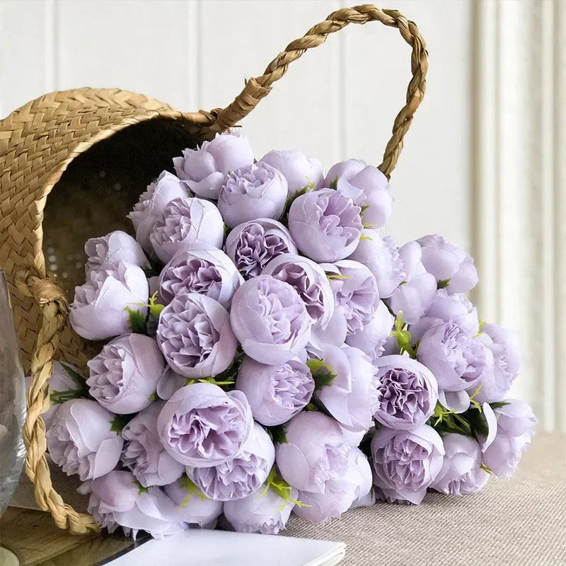 A woven basket tipped over, spilling out a large bouquet of light purple peonies with lush, maintenance-free faux petals and green leaves, set against a neutral background.