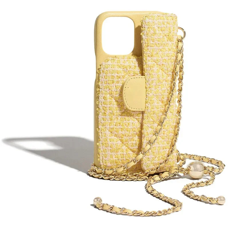 A yellow quilted phone case with a matching attached pouch and a stylish chain strap, decorated with pearl accents, is displayed upright on a white background.