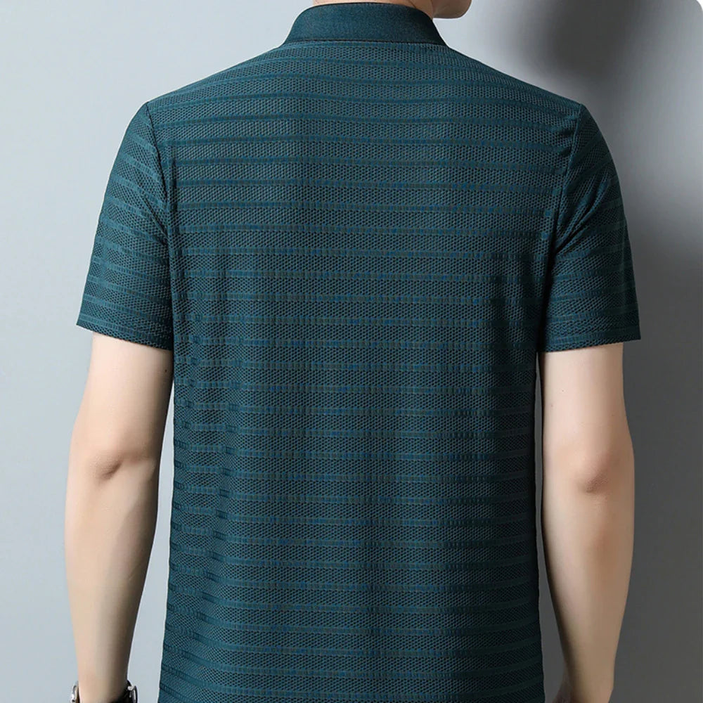 A person wearing a dark green classic polo shirt with a subtle pattern, shown from the back against a plain light gray background.