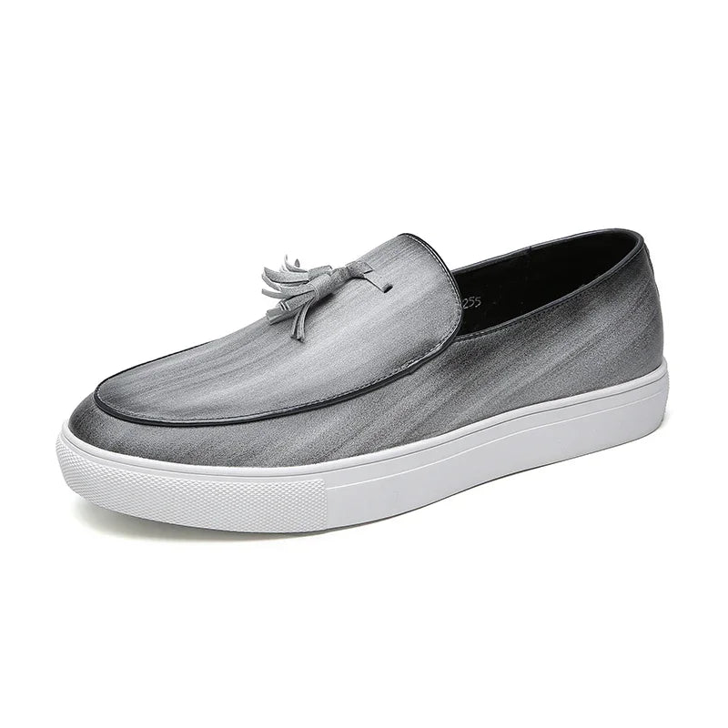 A gray tassel loafer with a white rubber sole and decorative tassel on the upper, featuring a cushioned insole for enhanced comfort, photographed against a white background.