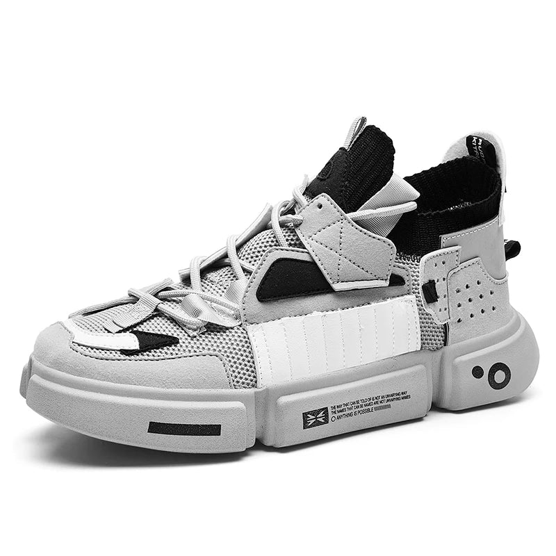 A modern, chunky streetwear sneaker in shades of grey, black, and white with a thick sole, detailed stitching, multiple overlays, and decorative text and symbols on the side. The shoe features unique geometric design elements for standout style.