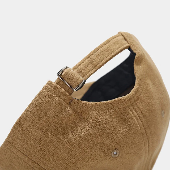 Close-up of the back of a tan suede baseball cap, showing an adjustable strap with a metal buckle and visible stitching. This unisex streetwear cap features a retro touch and is lined inside with dark fabric for added comfort.