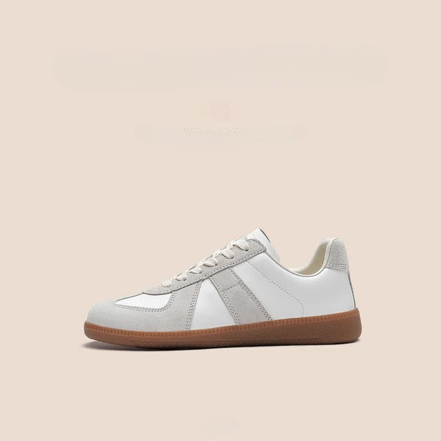 A white and light gray sneaker with a tan gum sole, shown in profile on a plain beige background. The shoe features lightweight breathable sneakers design, white laces, and premium cow suede detailing on the toe, heel, and sides.
