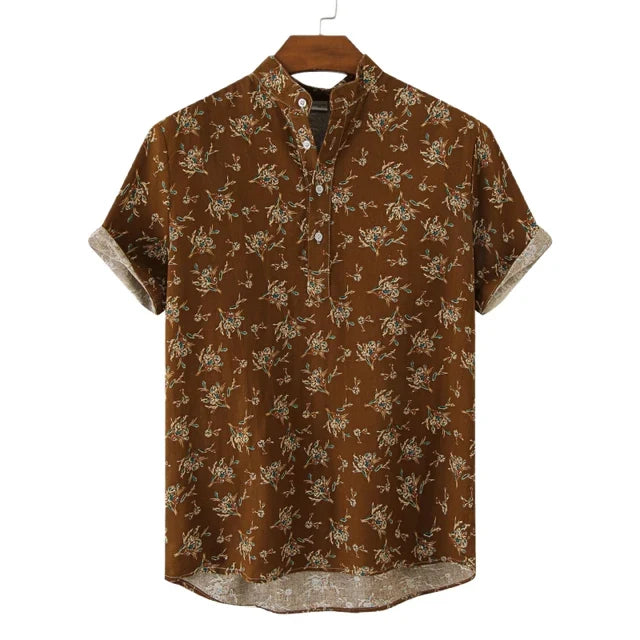 Brown short-sleeve casual shirt with a mandarin collar and a floral pattern in light colors, displayed on a wooden hanger against a white background. The cotton shirt features rolled-up sleeves and a buttoned placket.