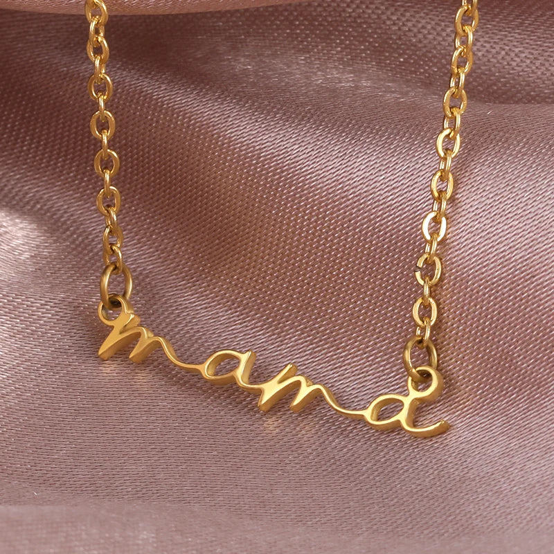 A gold-plated mama necklace with the word mama in cursive script, displayed on a soft, light pink satin fabric background—perfect as a thoughtful Mothers Day necklace.