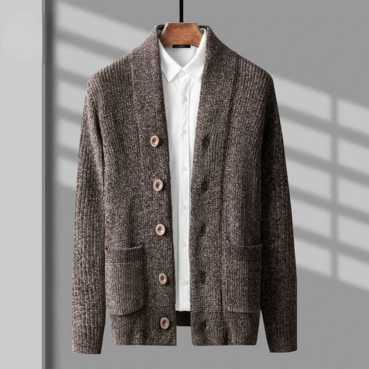 A brown textured knit cardigan in a classic button up style with large buttons and two front pockets, layered over a white collared shirt and displayed on a hanger against a gray background with shadow lines.