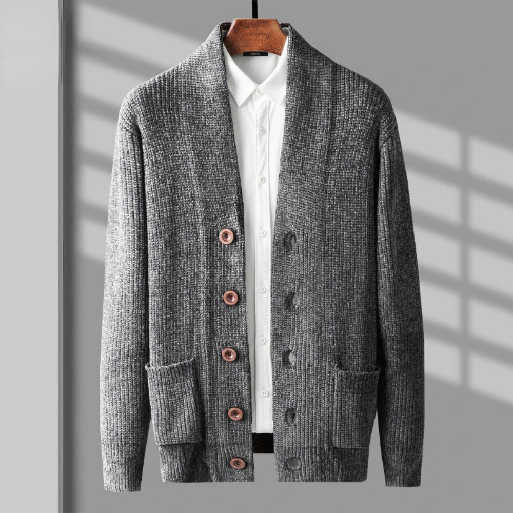 A gray cashmere wool blend cardigan with wooden buttons, two front pockets, and a white collared shirt underneath, perfect for layering, hangs on a wooden hanger against a gray background with shadows.