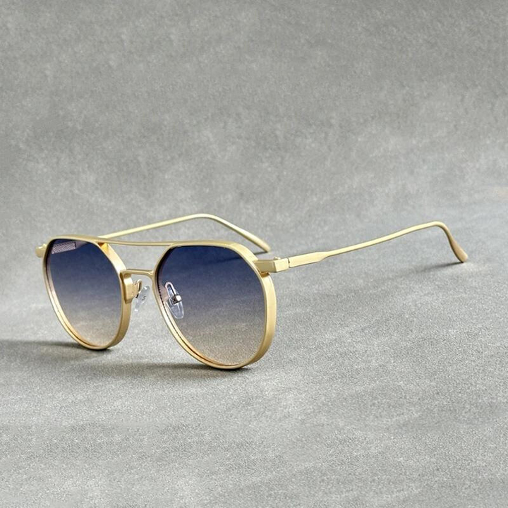 A pair of gold-framed sunglasses crafted from lightweight alloy with round, blue gradient lenses and UV400 protection is placed on a gray textured surface.