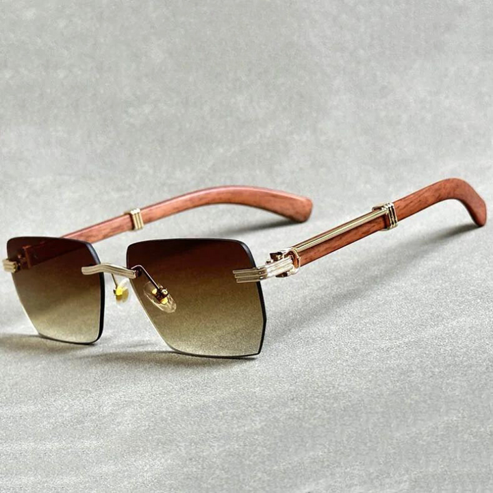 Rectangular rimless sunglasses with gradient lenses, gold accents, and stylish wooden temples, displayed on a light gray surface.