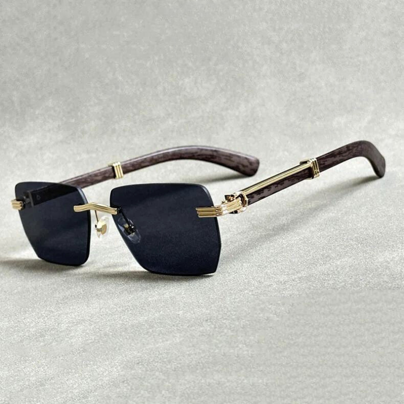 A pair of stylish rimless sunglasses with rectangular gradient lenses, gold metal accents, and brown wood-patterned arms, displayed on a light textured surface.