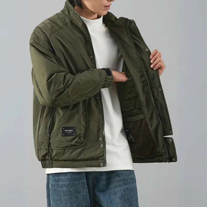 A person wearing blue jeans and a white t-shirt is opening a minimalist jacket to show its luxurious cotton lining and inner pocket. The image highlights the jacket’s details and functionality.