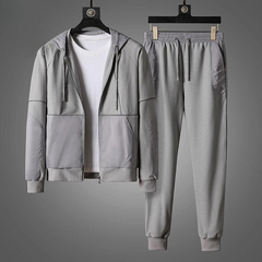 Gray activewear set featuring a zipper hoodie and matching jogger pants, displayed on hangers. Paired with a plain white T-shirt under the jacket, the moisture wicking outfit is set against a gray background.