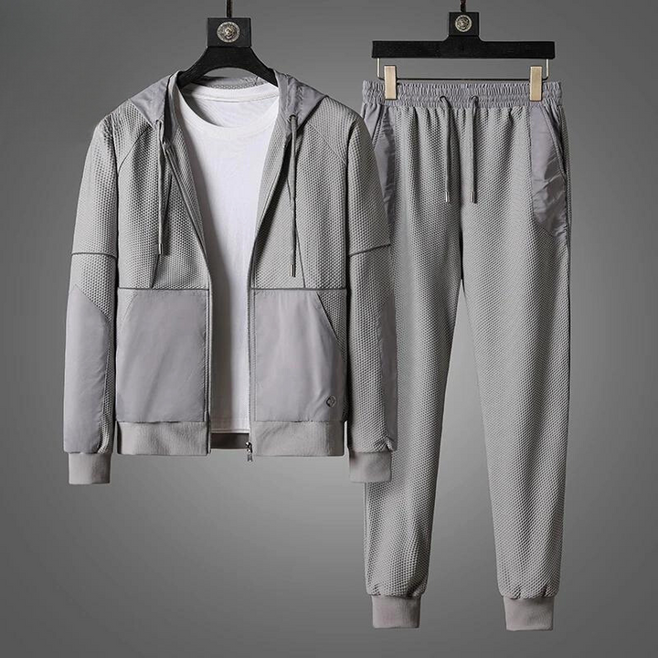 Gray activewear set featuring a zipper hoodie and matching jogger pants, displayed on hangers. Paired with a plain white T-shirt under the jacket, the moisture wicking outfit is set against a gray background.