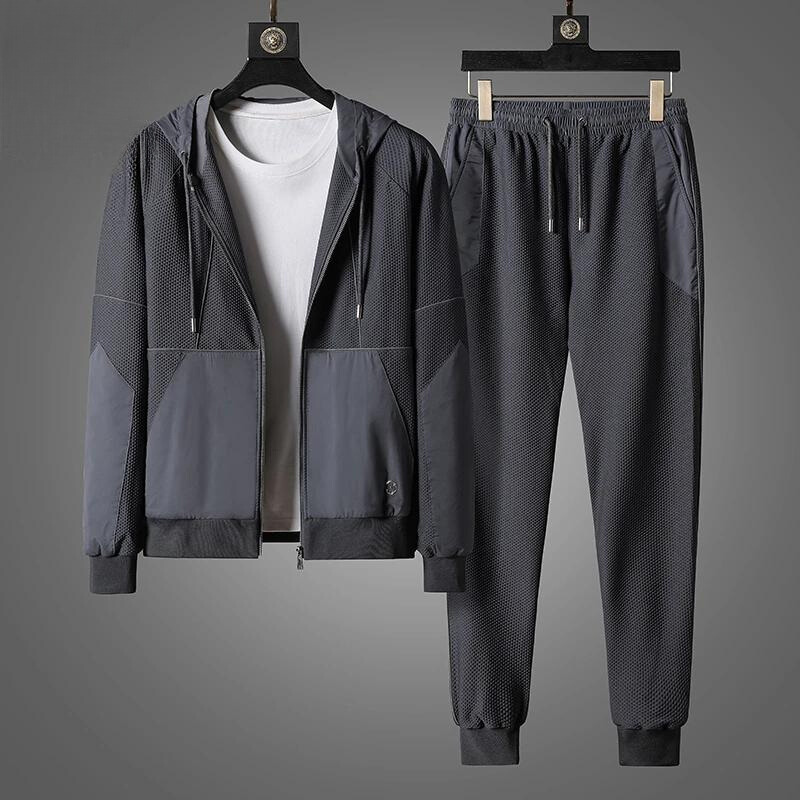 A dark gray zipper hoodie and matching jogger pants, crafted as an activewear set with a white T-shirt, are displayed on hangers against a gray background.
