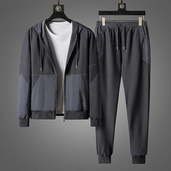 A dark gray zipper hoodie and matching jogger pants, crafted as an activewear set with a white T-shirt, are displayed on hangers against a gray background.