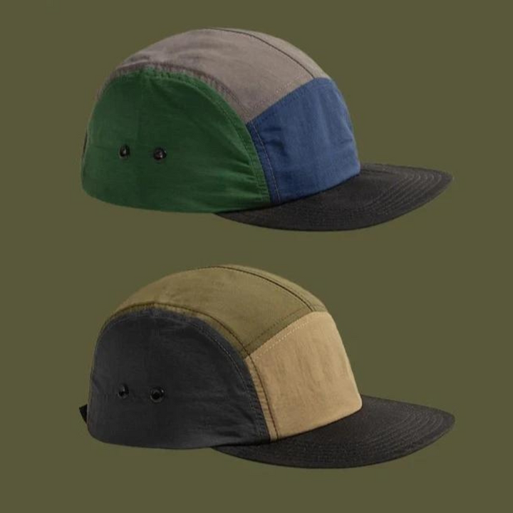 Two five-panel patchwork caps are displayed against an olive green background. Featuring earthtone aesthetics, the top cap has green, gray, blue, and black panels; the bottom blends olive, tan, gray, and black. Both have black brims.