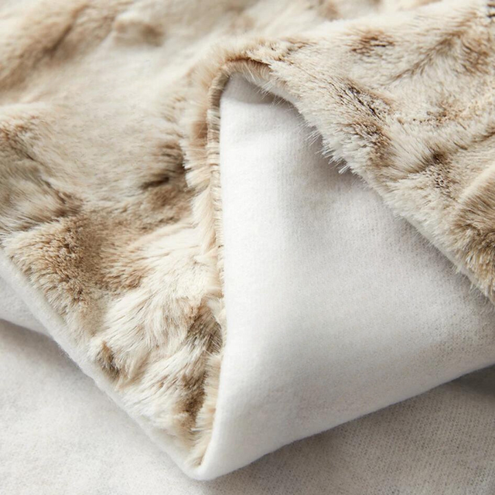 A close-up of an ultra-soft luxurious blanket in light brown faux fur with a white, smooth inner lining, highlighting its plush, textured surface and cozy material.