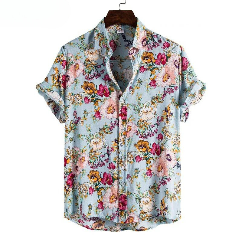 A short-sleeve, button-up, lightweight linen shirt with a light blue background features a vibrant floral pattern in pink, yellow, orange, and green. This vintage-inspired shirt is displayed on a hanger with the sleeves rolled up.