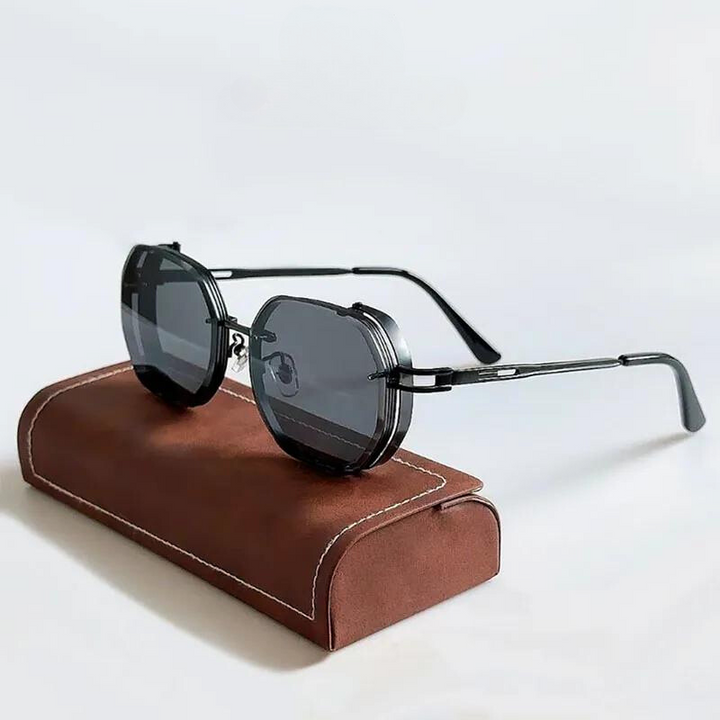 Round, black eclectic sunglasses with dark lenses rest on a brown, rectangular glasses case with white stitching, against a light gray background.