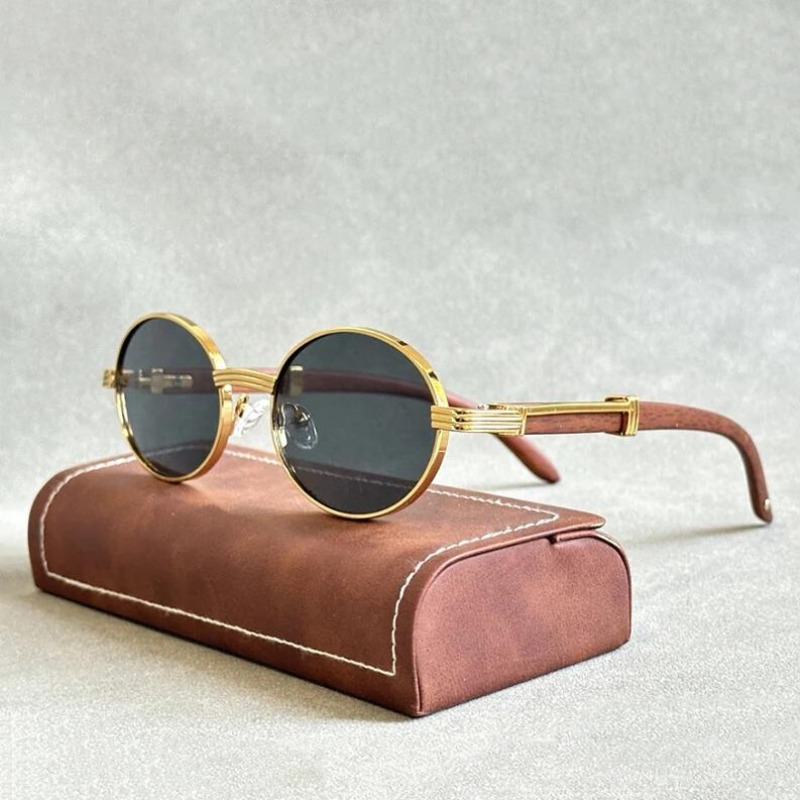 Vintage round sunglasses with gold frames and dark lenses rest on a brown, fabric-covered case featuring white stitching. The design’s UV400 protection blends style and safety against a neutral, textured background.