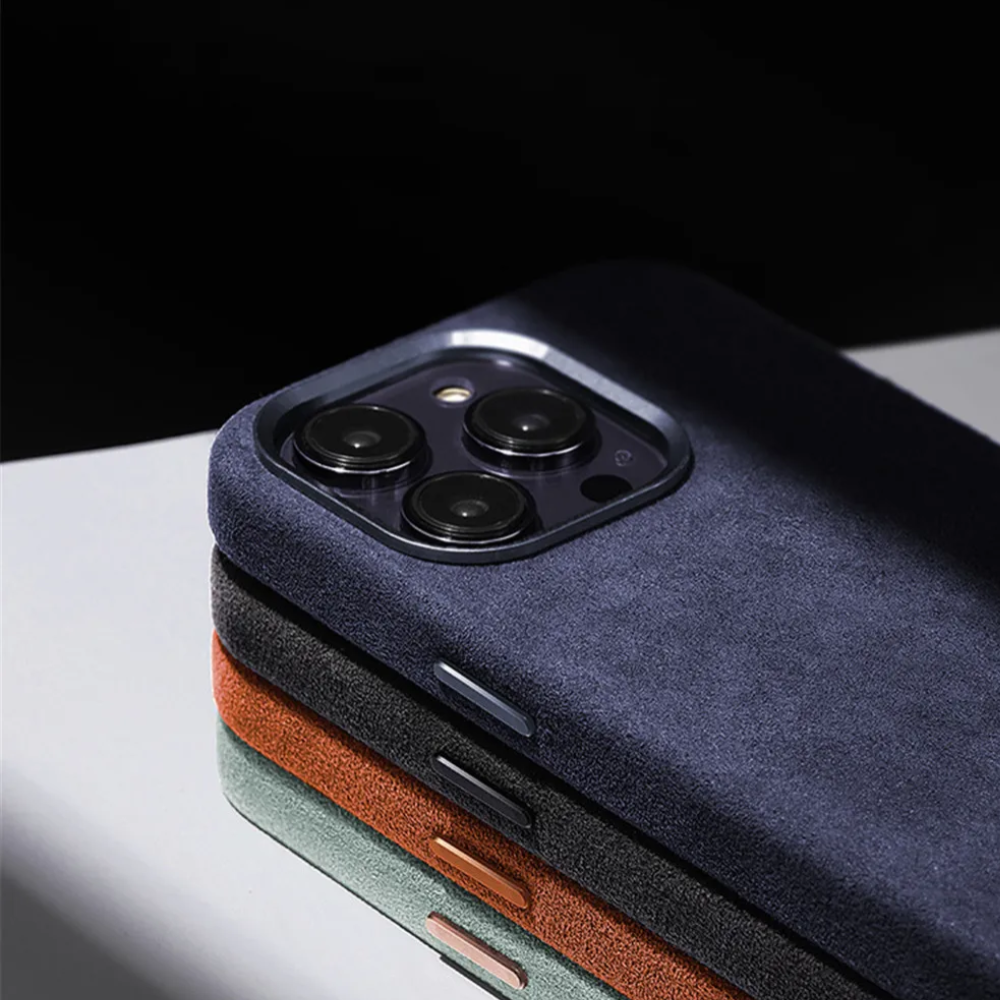 Three smartphones in stacked rows, each with a dark blue, green, or brown suede finish case showcasing the rear cameras and part of their edges. The protective design is highlighted against a reflective surface.