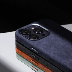 Three smartphones in stacked rows, each with a dark blue, green, or brown suede finish case showcasing the rear cameras and part of their edges. The protective design is highlighted against a reflective surface.