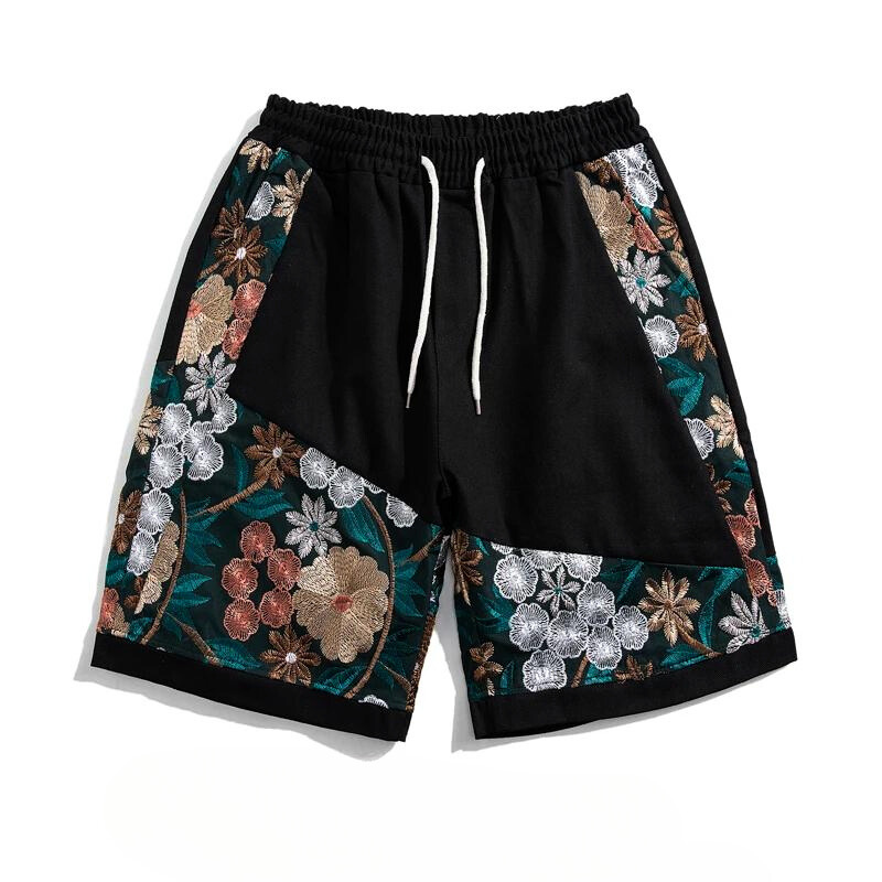 Black cotton shorts with a drawstring waist, featuring large, colorful summer florals in white, brown, and green embroidered along the sides, pockets, and lower legs—perfect for lightweight comfort.