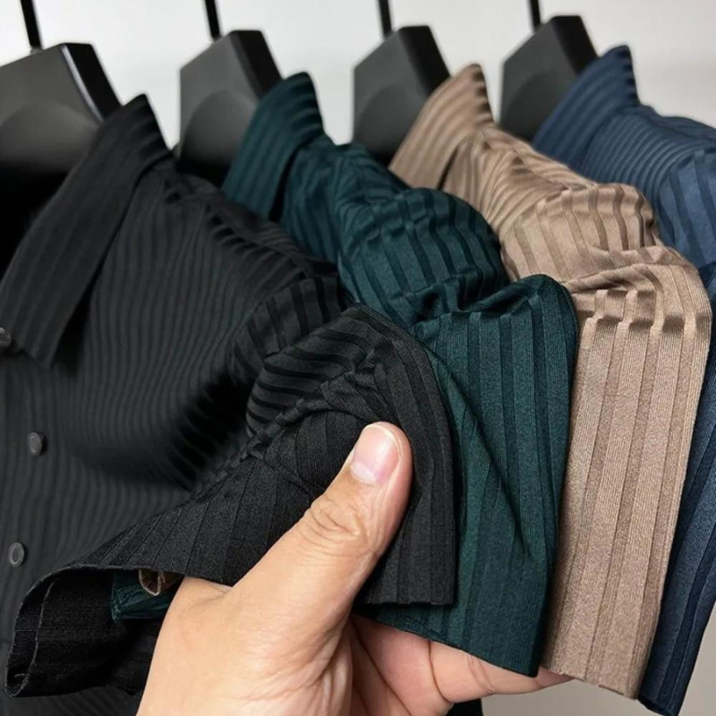 A hand holds the sleeves of four vertically striped collared shirts in black, green, brown, and blue, all hanging on black hangers—crafted from luxurious silk fabric for a premium feel and natural temperature regulation.