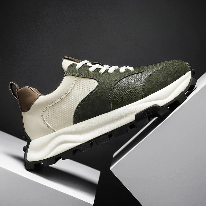 A stylish Onex Street Sneaker with a chunky white sole, olive green suede and textured leather upper, white side panels, and cloud-like cushioning, displayed on angled white platforms against a dark background.