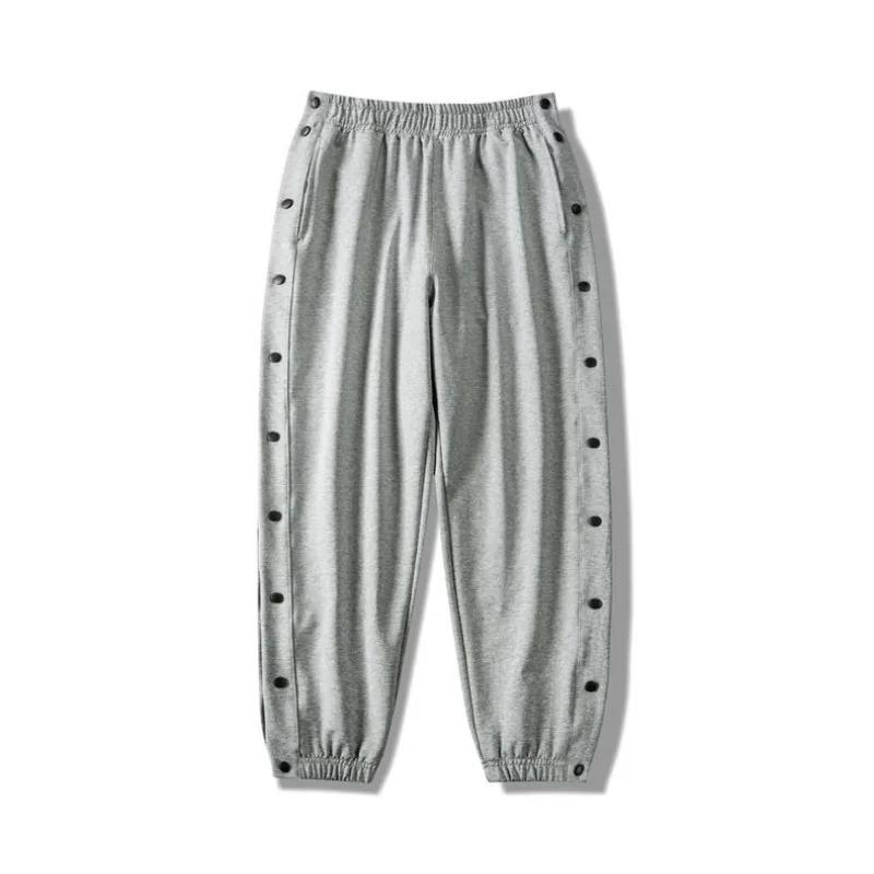 Light gray button-up gym pants with an elastic waistband and cuffs, featuring snap buttons down the sides of both legs and crafted from moisture wicking fabric for ultimate comfort.
