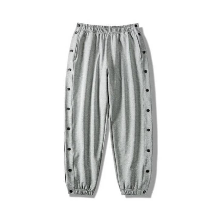 Light gray button-up gym pants with an elastic waistband and cuffs, featuring snap buttons down the sides of both legs and crafted from moisture wicking fabric for ultimate comfort.