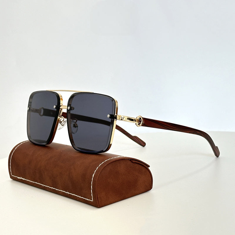 A pair of square, gold-rimmed vintage sunglasses with dark lenses and brown wooden arms, displayed resting on a brown suede glasses case against a plain light background.