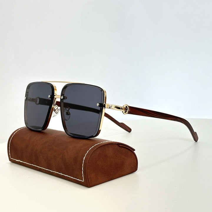A pair of square, gold-rimmed vintage sunglasses with dark lenses and brown wooden arms, displayed resting on a brown suede glasses case against a plain light background.