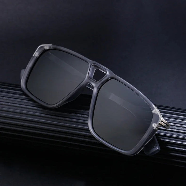 A pair of black square-framed polarized sunglasses with dark lenses rests on a textured black surface, set against a dark background, offering superior UV protection in style.