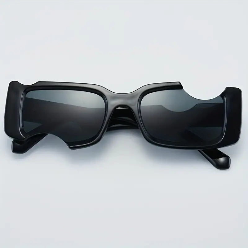 A pair of black sunglasses with an unusual, chunky geometric frame design and cut-out sections above the lenses, displayed on a light background.