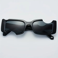 A pair of black sunglasses with an unusual, chunky geometric frame design and cut-out sections above the lenses, displayed on a light background.
