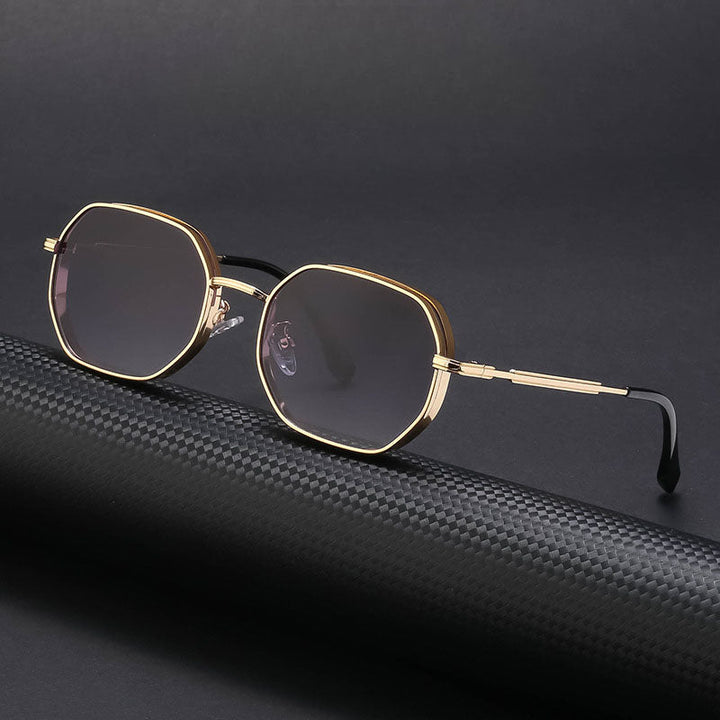A pair of vintage-inspired sunglasses with gold-tone frames, dark lenses, and black temple tips is displayed on a textured black surface against a dark background.