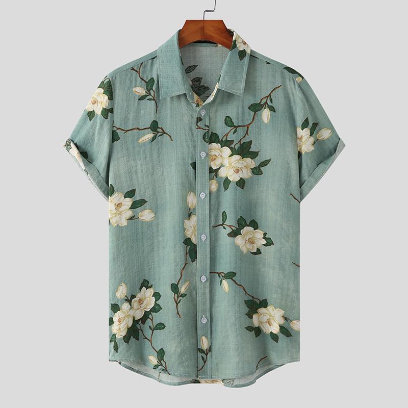 Short-sleeved, light teal Mens Hawaiian Shirt featuring white flower prints and green leaves, displayed on a wooden hanger against a plain light gray background.