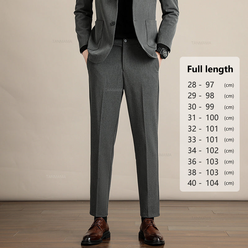 A person in a grey suit with hands in pockets stands indoors on a wooden floor. Beside them, a chart displays Mens Slim Casual Trousers full lengths in centimeters, ranging from 97 cm to 104 cm for sizes 28 to 40.