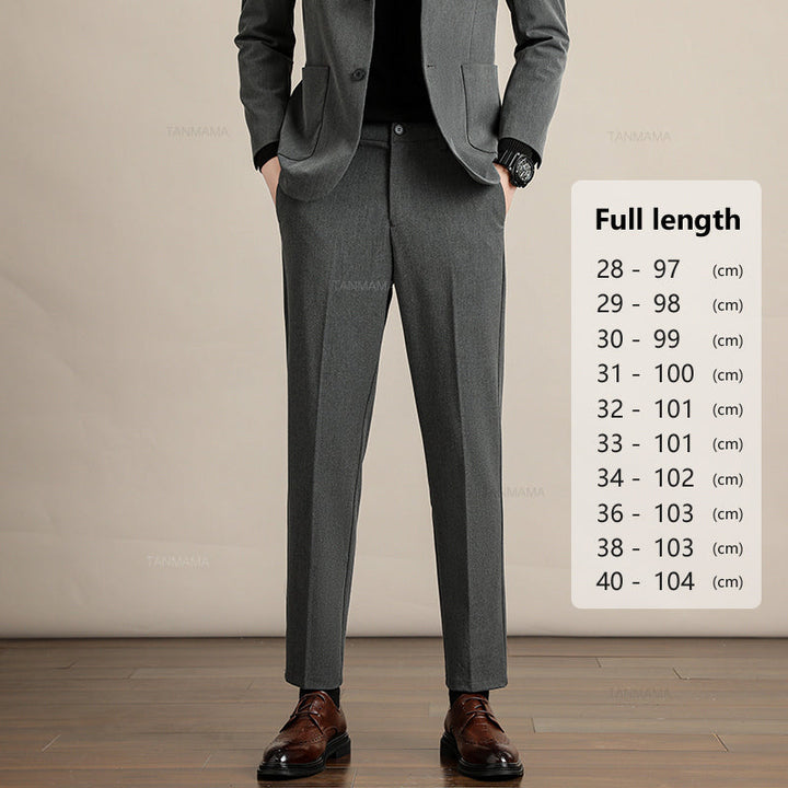 A person in a grey suit with hands in pockets stands indoors on a wooden floor. Beside them, a chart displays Mens Slim Casual Trousers full lengths in centimeters, ranging from 97 cm to 104 cm for sizes 28 to 40.